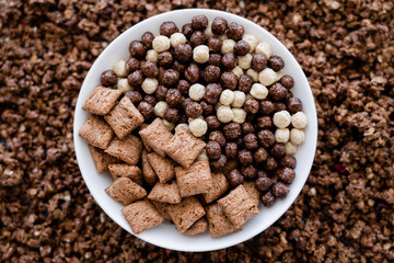 top view of bowl with tasty cereal balls and puffs near granola.