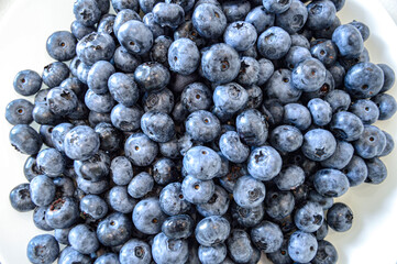 Blueberries lie on a white table. Harvest, vitamins, juicy appetizing berries. Gifts of nature. Healthy snack, vegetarianism, raw food diet. Dietology, nutrition. Background, texture, postcard