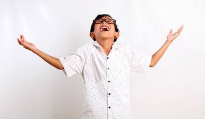 Excited asian schoolboy standing while looking up with surprised expression. Isolated on white