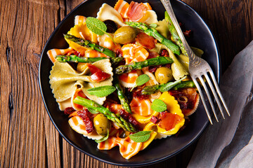 Pasta salad with green asparagus, olives and parma ham