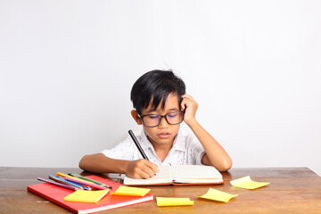 Thoughtful Asian schoolboy studying in the classroom. Isolated on white background