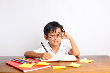 Tired Asian schoolboy studying in the classroom. Isolated on white background