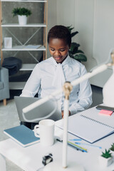 Charming happy young black businesswoman sitting at office table working on the project on laptop. Business portrait. Internet network. Fashion model. Internet