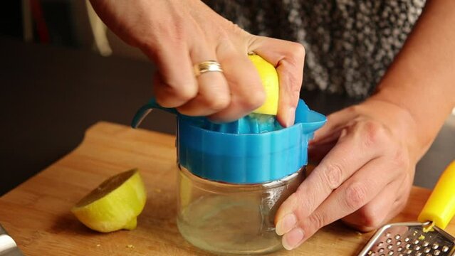 Hands of woman squeezing lemons with juicer