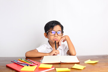 Sad asian schoolboy studying in classroom with frown face. Isolated on white background