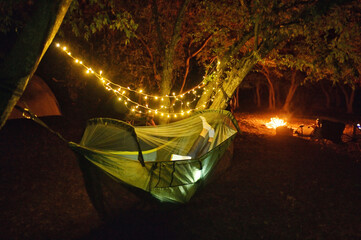 Camping in Night Forest With Sparklers. Woman Lying In Hammock