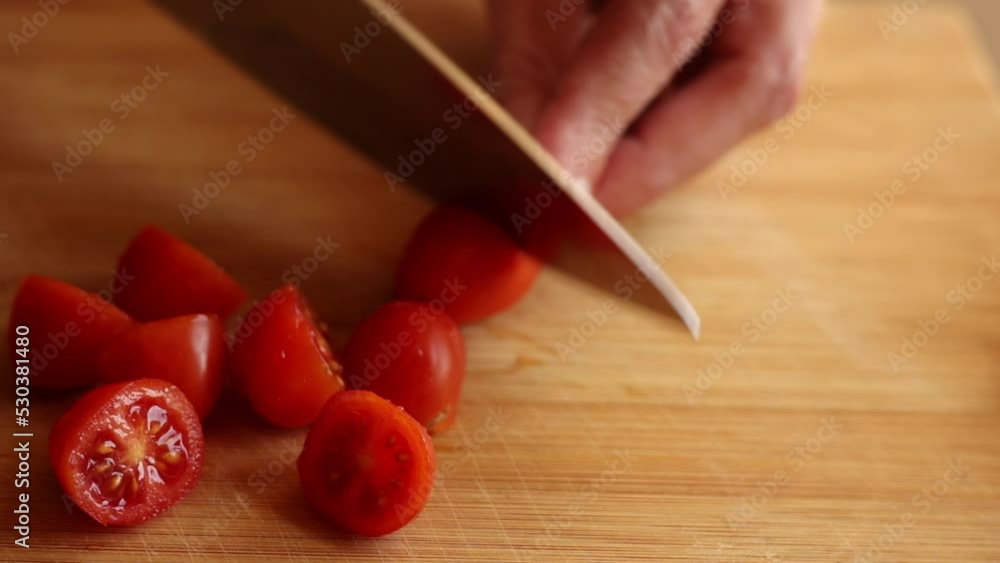 Wall mural cutting cherry tomatoes at home on wooden board