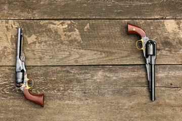 Two black powder revolvers Colt Army and Remington New Army on an old board form a frame - obrazy, fototapety, plakaty