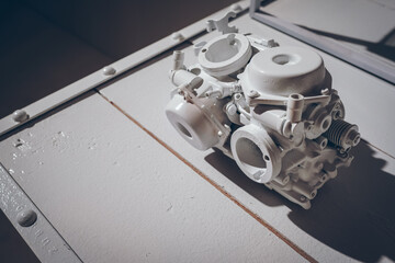 White carburetor engine of motorcycle on metal table in all white garage, with blank copy space, motorcycle fragment