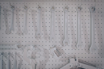 White workshop scene. tools hanging on wall in workshop, Tool shelf against a table and wall, all white color concept for custom bike