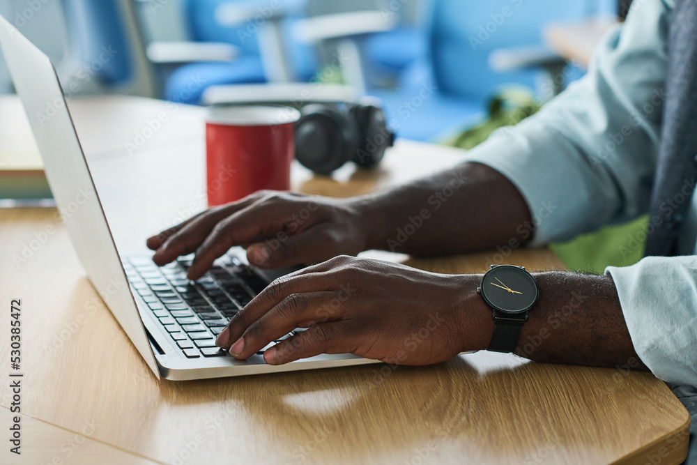 Aufkleber hands of young african american businessman typing on laptop keypad while sitting by workplace in of