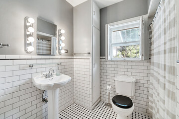 Beautiful bathroom in home with toilet, mirror, sinks, shower, tiled floor, and gray accents