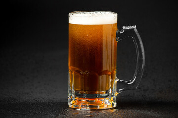 Pouring a glass of brown beer on a rough wooden table