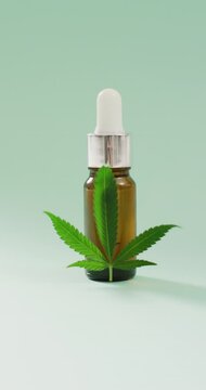 Vertical video of marijuana leaf and bottle of cbd extract on blue background