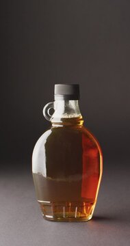 Vertical video of maple syrup in glass on grey surface