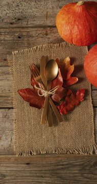 Vertical video of cutlery, cloth and pumpkin lying on wooden surface