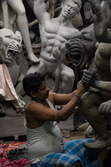 A man painting Durga idol with use of selective focus on a particular part of the man with rest of...