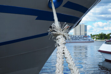 The bow of a ship with a mooring cable with a shaggy knot against the background of the river.