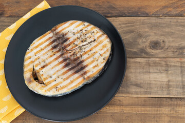 Grilled tuna slice on a wooden plate. Copy space. Top view. Thunnus.