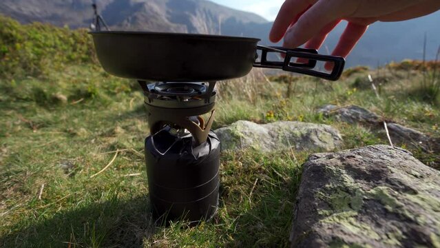 Setting up a camping stover and frying pan in the mountains