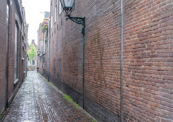 Leiden town Netherlands. Traditional red brick wall building, complicated lantern, cobblestone path.