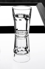 A glass with clean clear water with reflection and sharp shadows
