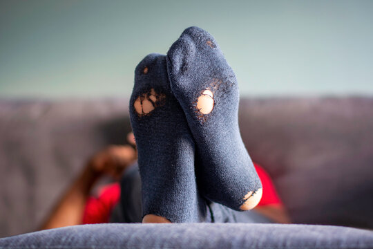 Bottom of worn out socks. Man wearing old socks with holes in it, relaxing on the couch at home.