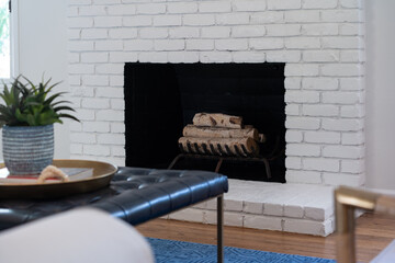 Living room detail of painted brick fireplace and leather coffee table.