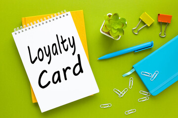 loyalty card. business concept. bright background, blue notepad and potted plant. text on paper. green background