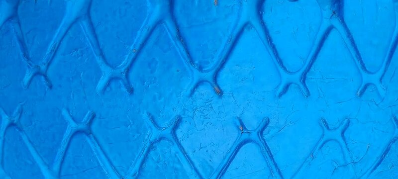 Background of a car tire painted blue. The diamond-shaped backdrop is blue paint with copy space.