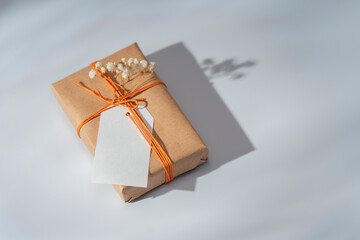 Kraft gift box with orange thread and labels for inscriptions on a light background. Packaging and...
