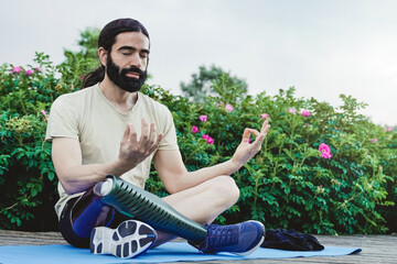 Young man with leg prosthesis doing meditation outdoor - Health care and disability concept