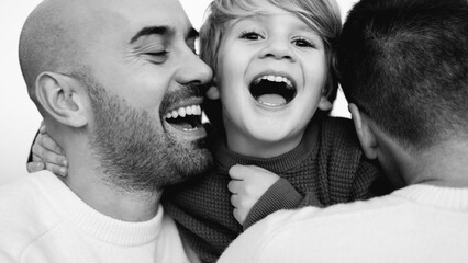 Gay male parents having tender moment kissing their son outdoor - Focus on kid face