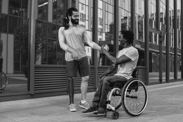 Multiracial people with physical disabilities greeting each other outdoor - Focus on African man sitting on wheelchair - Black and white editing