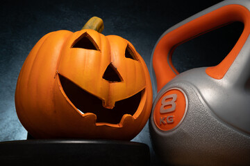 Ceramic Halloween pumpkin with heavy kettlebell gym exercise equipment. Healthy fitness lifestyle...