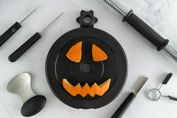 Dumbbell barbell weight plate with Halloween pumpkin pieces cut out. Carved face elements with...