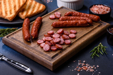 Delicious fresh smoked sausages cut with slices on a wooden cutting board