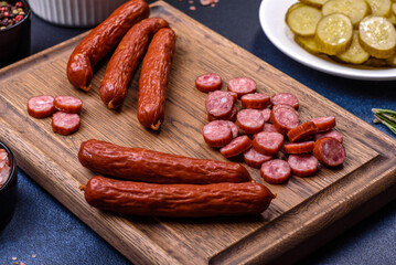 Delicious fresh smoked sausages cut with slices on a wooden cutting board