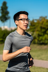 Close up portrait of adult asian man jogging in park.