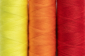 Bright sewing thread spools close up, full frame background, top view.