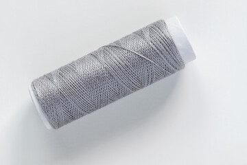 Grey sewing thread spool on white background.