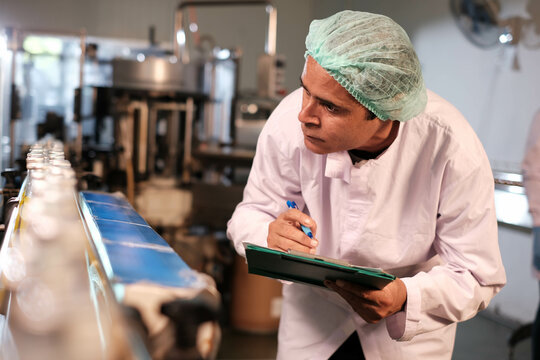 Professional engineering, worker, man Quality control, maintenance, check in factory, man worker checking stock of products in beverage factory. Worker QC working in a drink water factory.