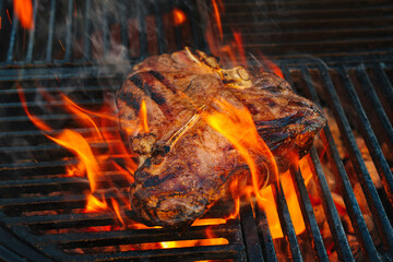 Barbecue dry aged Wagyu Porterhouse Steak vom Rind gegrillt als close-up auf einem Holzkohle Grill mit Feuer und Rauch
