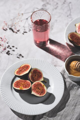 Top view flat-lay still life with fresh cut figs on plates with honey and drink