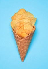 Waffle Cone with Potato Chips on blue background. Fast Food concept