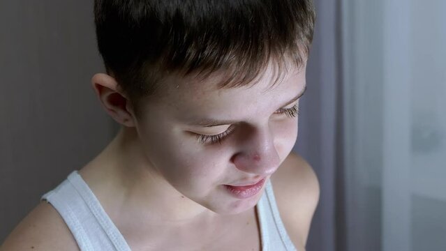 Face of a Guilty, Speaking Smiling Teenager with a Downcast Look. Side view. Conflict with parents, repentance, punishment, awareness of guilt. Behavior, emotion, reaction, dialogue. Childhood age.