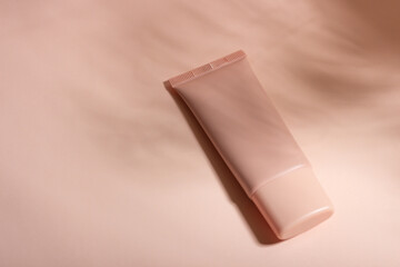 Cosmetic cream or mask in a white tube with hard shadows from the leaves on a white background. Natural organic care for face and body skin. View from above.