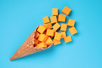 Waffle Cone with Yellow Cheese Cubes on blue background