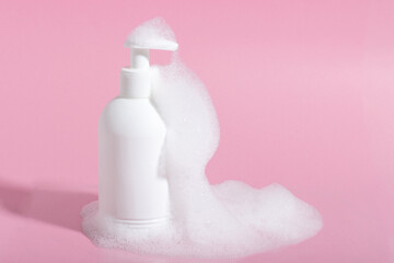 Cosmetics for face, body and hair care. Moisturizer, shampoo or facial cleanser on pink background with foam