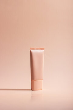 Cosmetic cream or mask in a white tube with hard shadows from the leaves on a white background. Natural organic care for face and body skin. View from above.